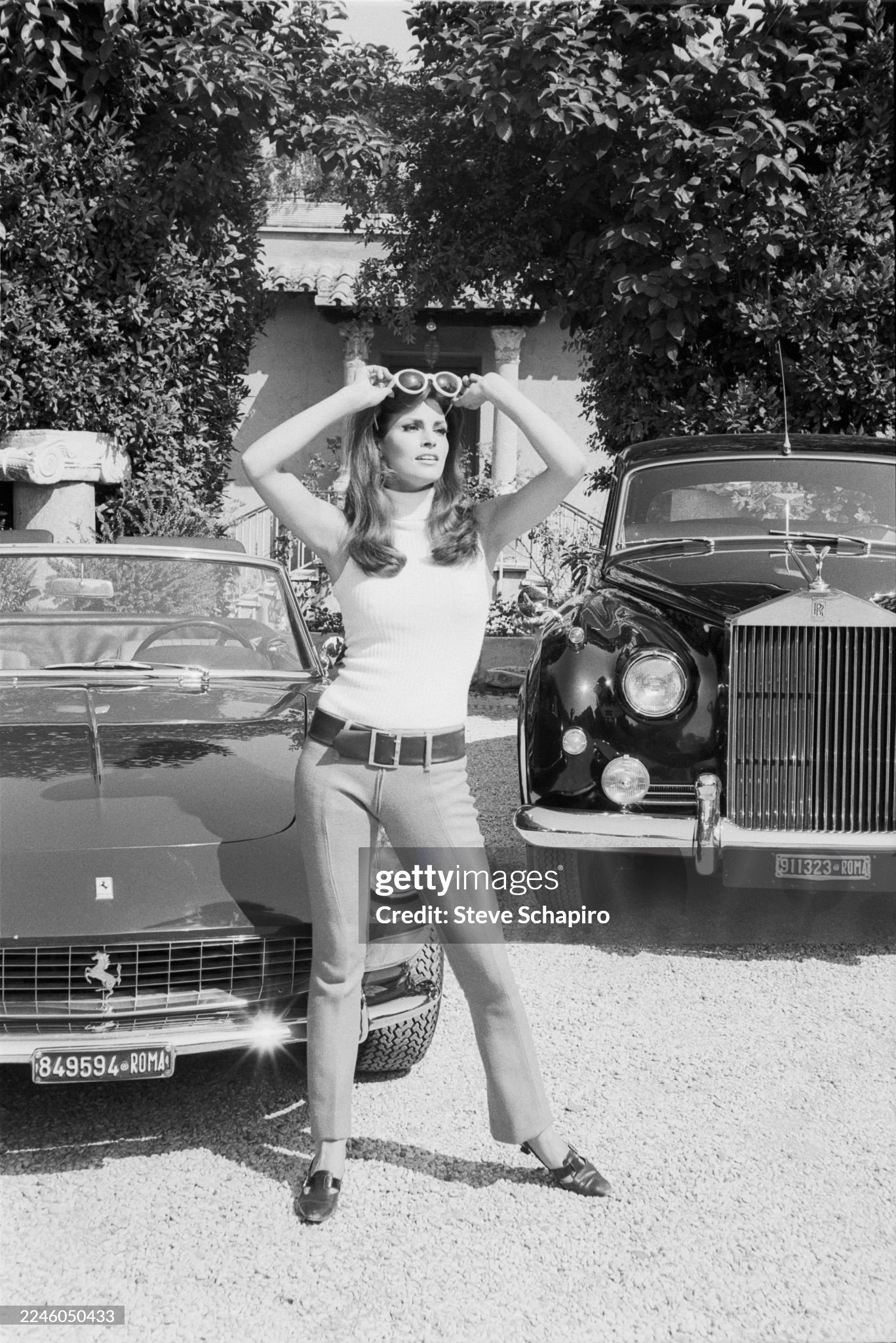 American actress and model Raquel Welch poses in front of a Ferrari and a Rolls Royce in a driveway in Rome, Italy, in July 1966. 