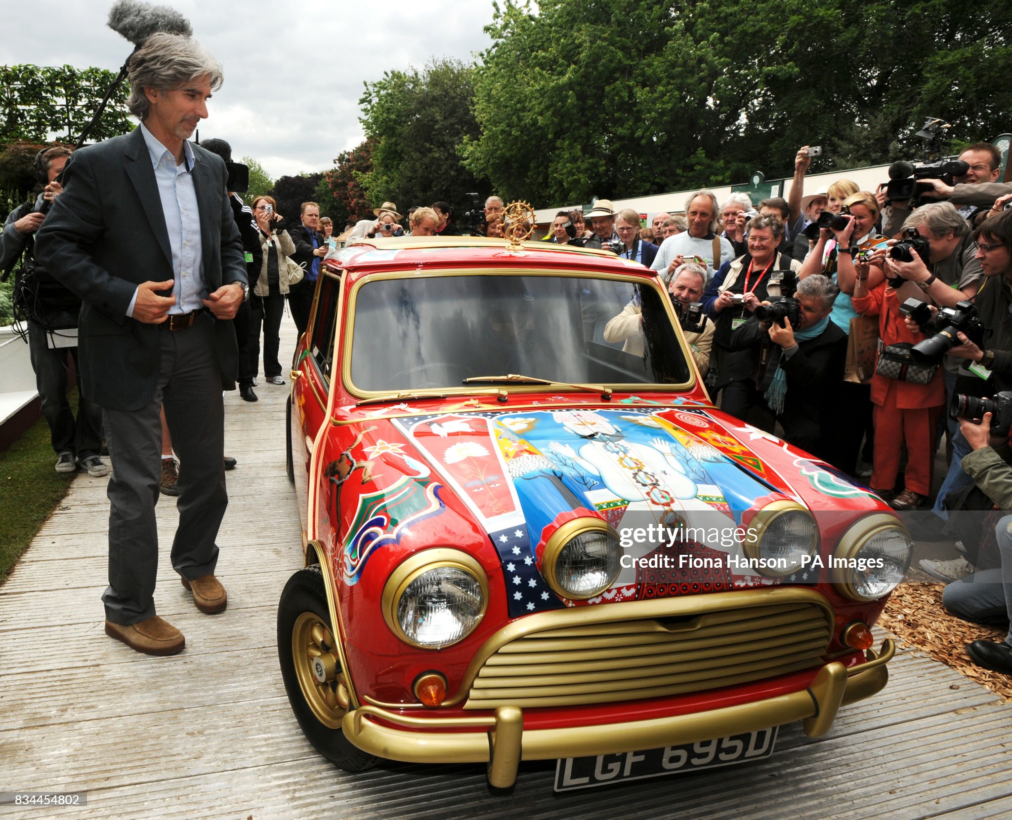 Former British F1 driver Damon Hill looks at a decorated Mini Cooper owned by the late Beatles bassist George Harrison.