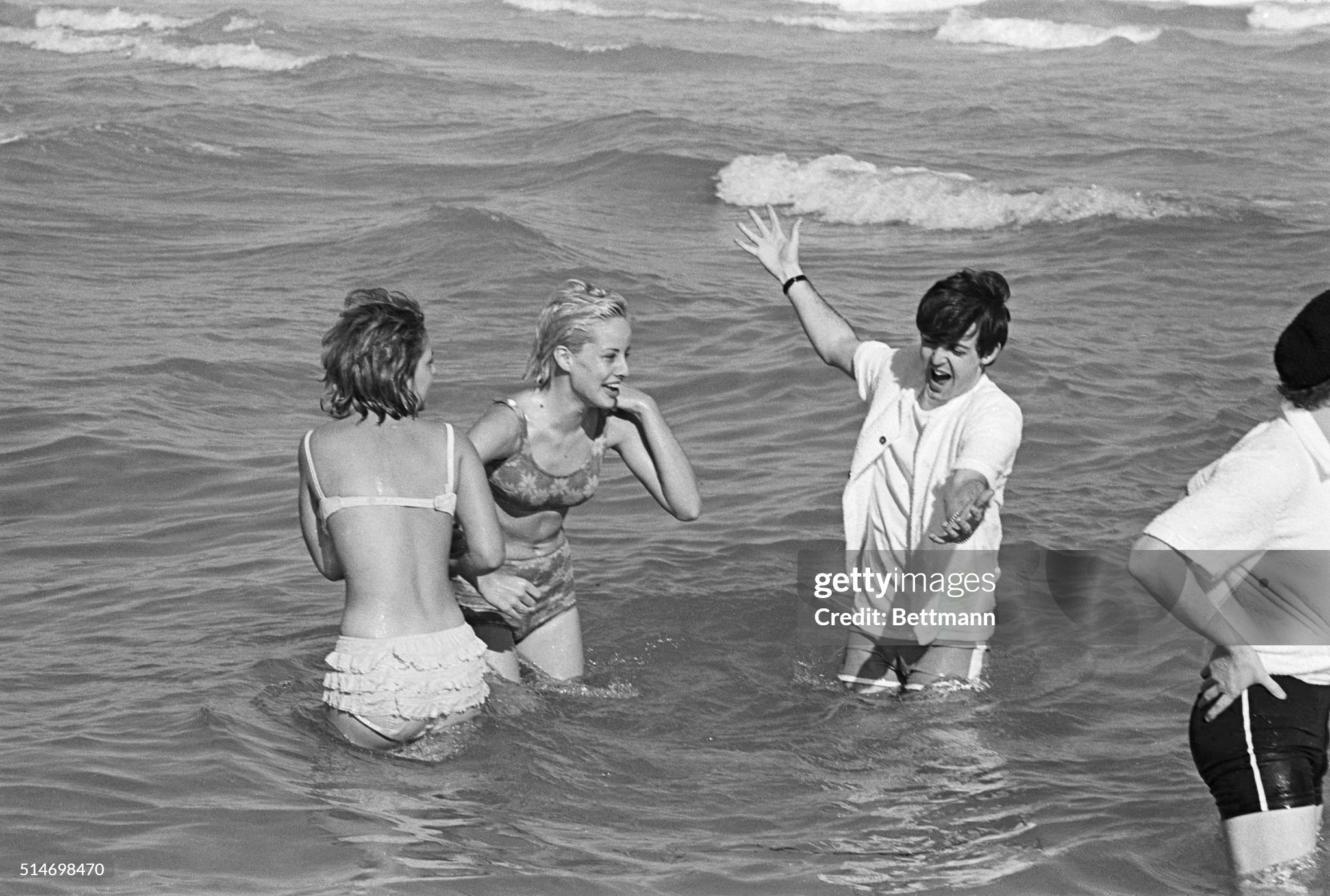 Paul McCartney, taking advantage of some relaxation time on the Beatles' 1964 concert tour, splashes in the Atlantic at Miami Beach with two girls on 15 February 1964. 