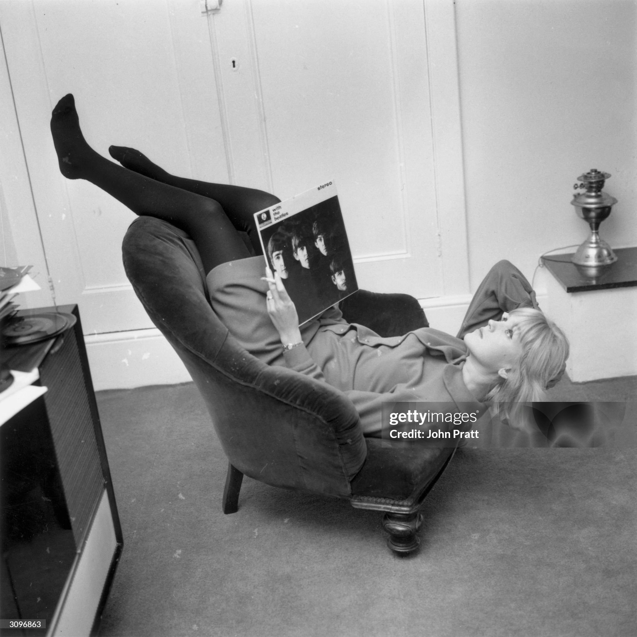 British disc jockey and television presenter, Annie Nightingale, relaxing at her home in Brighton with a copy of the Beatles album 'With the Beatles' on 14 December 1964. 