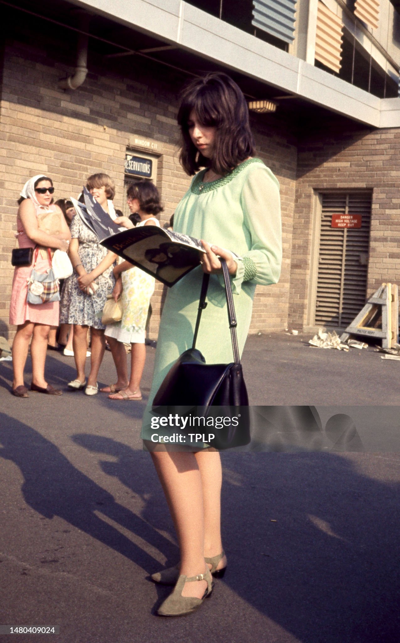 An unidentified teenaged woman reads the program prior to the concert with The Beatles at Shea Stadium in New York, on 15 August 1965. 