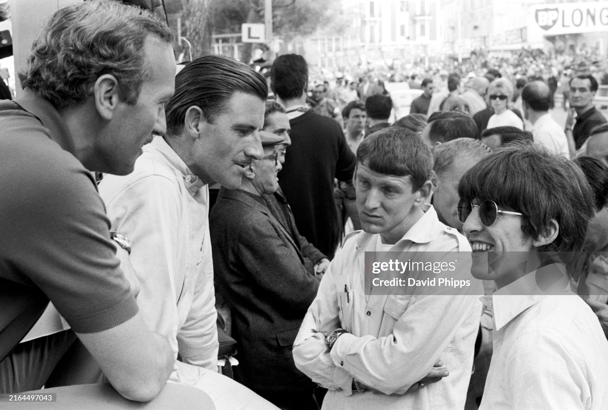 Colin Chapman, Lotus team owner, third placed Graham Hill, BRM and Keith Greene talk with Beatle George Harrison at the Monaco Grand Prix in Monte Carlo on 22 May 1966.