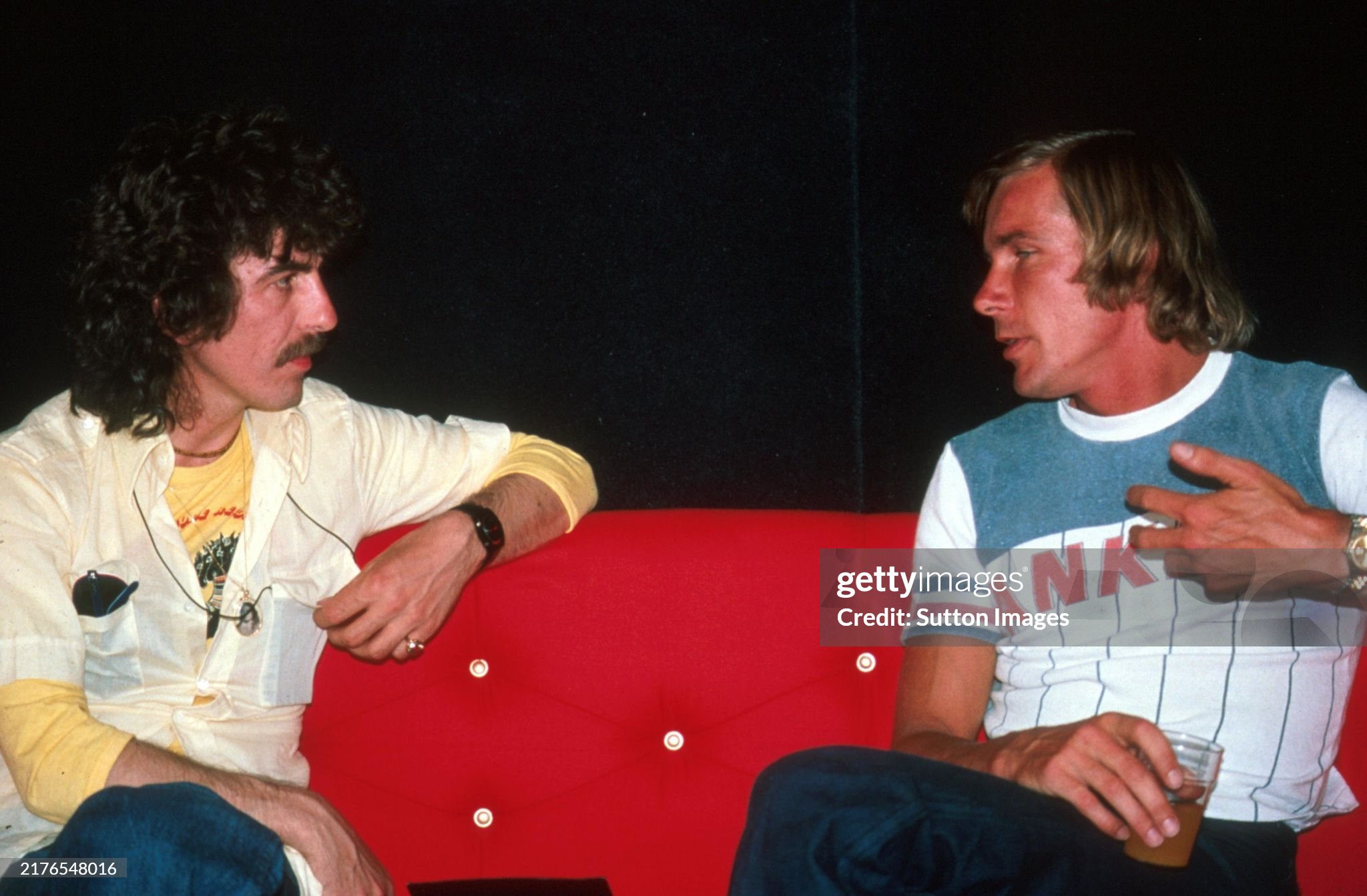 George Harrison enjoys a cigarette and a chat with race retiree James Hunt, McLaren, in the Marlboro motorhome at the Spanish Grand Prix in Jarama on 08 May 1977. 