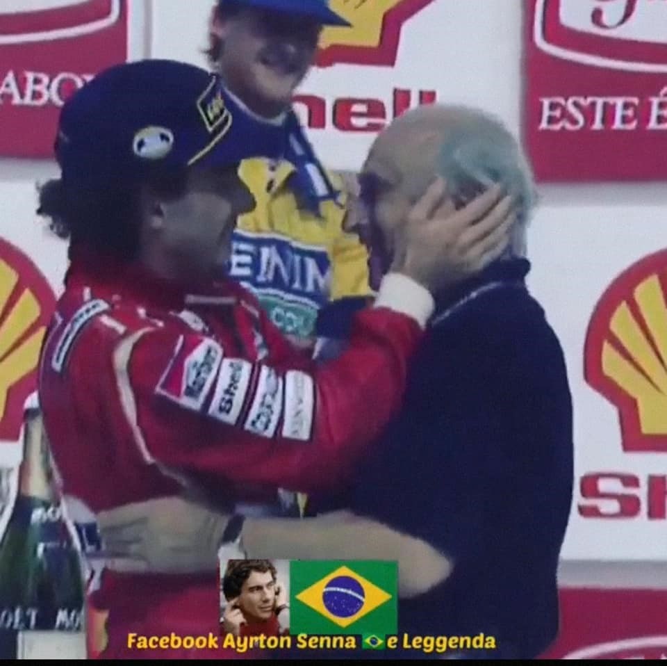 Ayrton Senna on the podium hugging Juan Manuel Fangio.