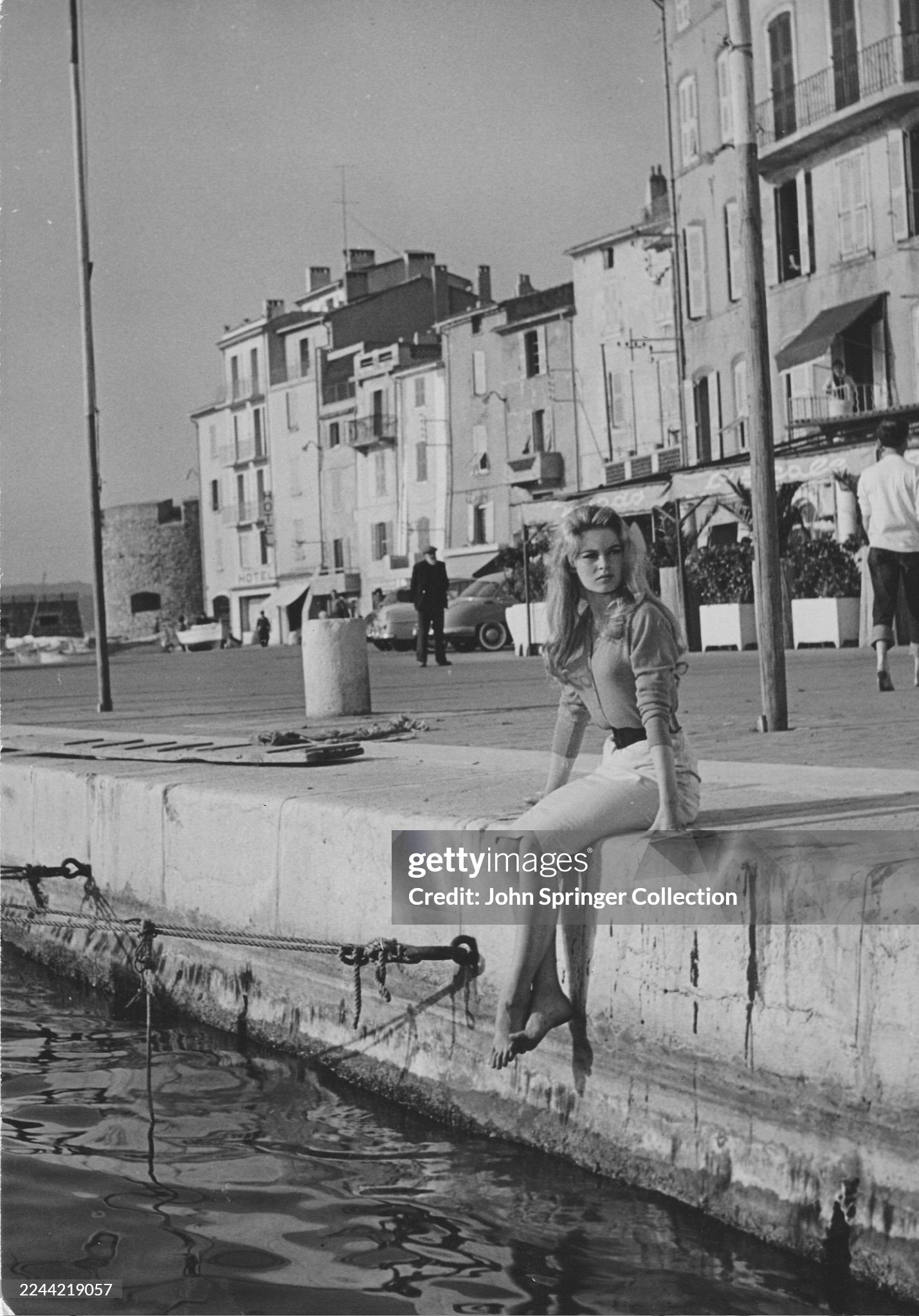 Brigitte Bardot sitting on a quay by the ocean in Saint-Tropez in the 1956 film directed by Roger Vadim, 'And God created woman’.