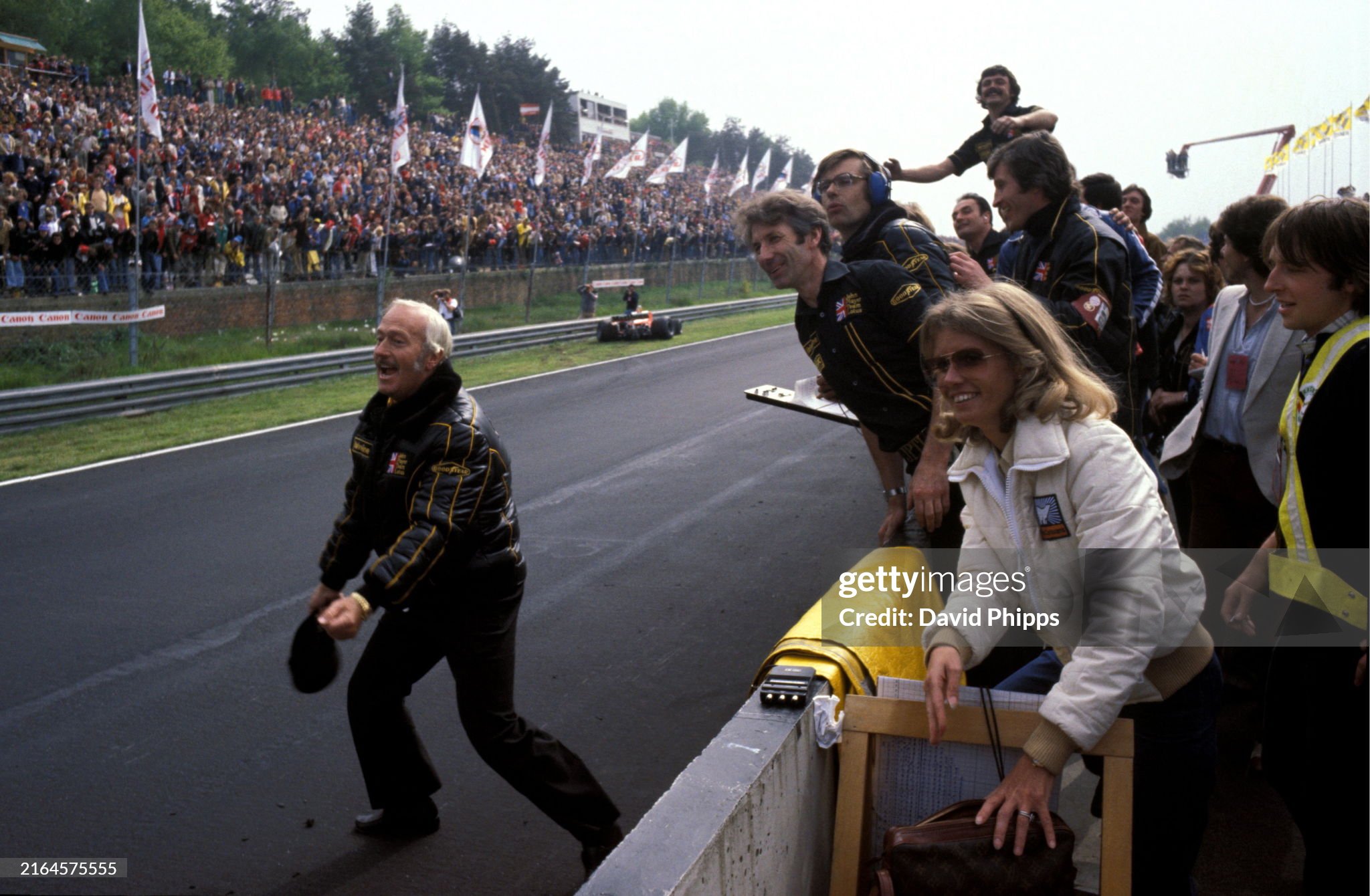 Colin Chapman prepares to perform his customary celebrations after a victory for Mario Andretti, Lotus. Long serving Lotus mechanic Bob Dance is hanging over the pit wall to Chapman's right and, at the top, Glenn Waters waves. Barbro Peterson is in the foreground at the Belgian Grand Prix in Zolder on 21 May 1978. 