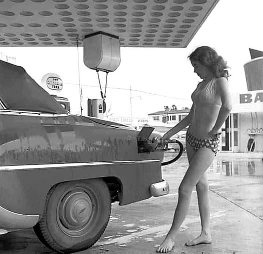 A vintage girl gases up a car.